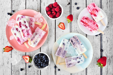 Wall Mural - Table scene of homemade berry yogurt ice pops. Above view with a rustic white wood background.