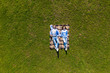 © F8  \ Suport Ukraine - Young couple in love lying on the grass looking up. Aerial view.