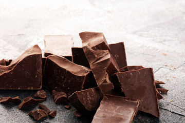 close up of bitter chocolate bars and broken piesces on rustic background.