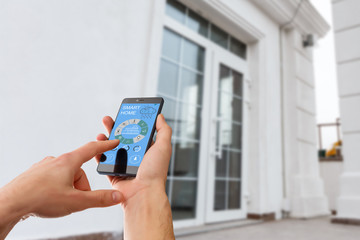 smart house, home automation, device with app icons. Man uses his smartphone with smarthome security app to unlock the door of his house.