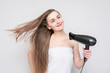 © Анастасия Семашко - Joyful girl with hair dryer, portrait, white background. Concept of hair care