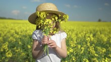 Little Beautiful Happy Girl Smiles In A Yellow Field Hides Behind A Bouquet Of Yellow Flowers