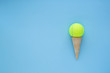 Yellow tennis ball in ice cream waffle cone , summer sport concept, on blue background . Space for text. 