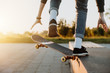 Junger moderner Skater mit Jeans skatet mit seinem Skateboard im Skatepark und macht einen Trick und grinded bei Sonnenuntergang
