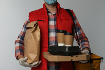 Sticker - Courier in protective gloves holding order on light background, closeup. Food delivery service during coronavirus quarantine