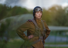 A Young Female Pilot In Uniform Of Soviet Army Pilots During The World War II. Military Shirt With Shoulder Straps Of A Major, Parachute, Flight Helmet And Goggles.