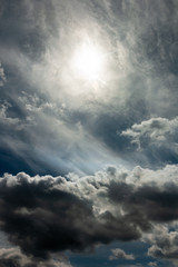 Wall Mural - dramatic stormy sky with a blurred sun disk and heavy cumulus clouds against a dense cloud cover. artwork picture for fantasy, abstract or moody design or decoration