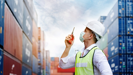 Engineers or foreman use walkie-talkie. In order to move container and shipping Safety helmet, accident from various equipment in factory. Mask protect dust, Coronavirus and spread germs while working