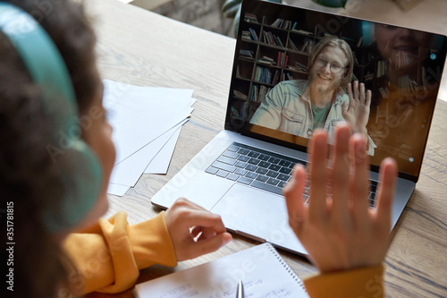 Cuadros en Lienzo Hispanic teen girl school college student distance learning waving hand studying with online teacher on laptop screen