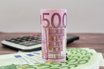 500 euro banknote rolled into a roll on the background of money and a calculator. Business concept.