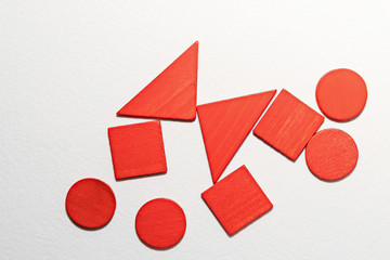 Different red shapes wooden on white background. Top view. Concept of geometry. Copy space. Children educational logical task. Flat lay.