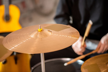 Round golden color cymbal as part of drum set on background of drummer