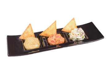 Gourmet Appetizer with nachos and three different salads, on a black plate, isolated on white background