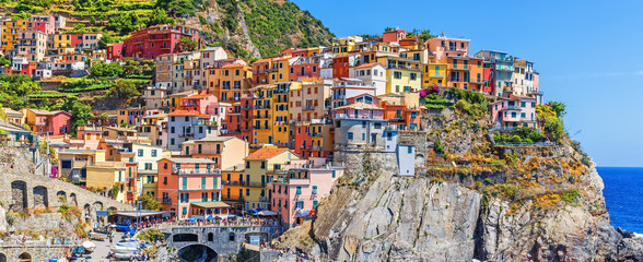 Wall Mural - Panoramic view of Manarola village in Cinque Terre famous UNESCO travel destination in Italy. Colorful houses at cliff, ancient European village at Mediterranean sea.