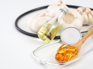 Capsule garlic oil in wooden spoon with fresh garlic, the benefit of garlic is prevent the occurrence of heart disease