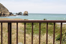 Scenic View Of Sea And Shore With Metal Railing In Foreground