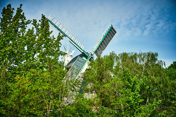 Historic and restored windmill in Berlin, Germany, between trees in spring.