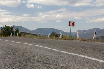 Empty road with a road sign, dangerous turn. Road landscape. Crimea.