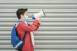 © esthermm - kid with medical mask and backpack screaming with megaphone back to school