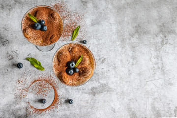 Wall Mural - Tasty Italian tiramisu in a glass cup with mint and blueberries with copyspace on a gray background