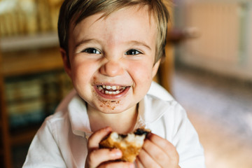 Happy baby eats sweet chocolate cake.