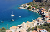 Fototapeta Do akwarium - Three white yachts in the background of the beautiful turquoise Mediterranean Sea. In the foreground are several old stone houses of Peloponnese, Greece.