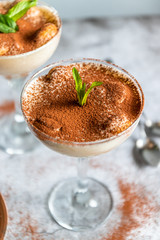 Wall Mural - Tasty tiramisu in glass, mint leaves and strainer with cocoa on gray background, vertical