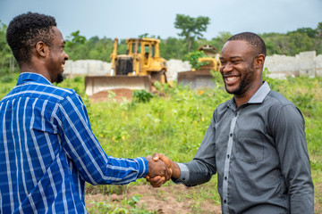 Wall Mural - two young african modern farmers shake hands, smiling