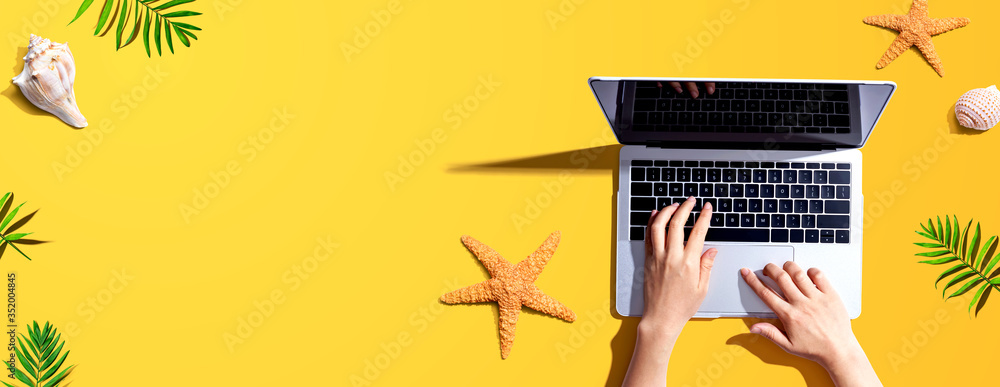 Person using a laptop computer with summer theme objects - flat lay - obrazy, fototapety, plakaty 