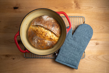 Homemade boule (round loaf) of freshly baked sourdough bread in a red Dutch oven