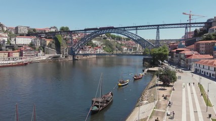 Wall Mural - AERIAL DRONE FOOTAGE - The iconic Rabelo Boats, the traditional Port Wine transports, with the Ribeira District and the Dom Luis I Bridge over the Douro River, Porto, Portugal. Unesco World Heritage.