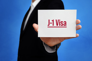 Wall Mural - J-1 Visa. Lawyer holding a card in his hand. Text on the board presents term. Blue background. Law, justice, judgement