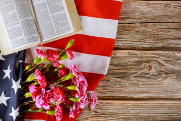 Wall Mural - Carnation flowers on Open reading Bible on a close up in the American flag