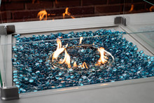 Modern Lit Gas Fire Pit With Blue Glass Marbles In An Outdoor Setting