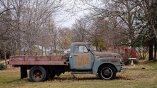 Abandoned Pick-up Truck On Field Against Trees