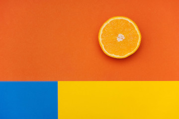 Sliced orange on a colorful background. Orange, yellow and blue colors.