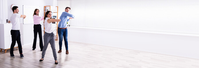 Businesspeople Doing Stretching Exercise At Workplace