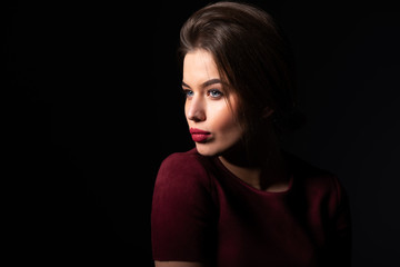 Leinwandbilder - Portrait of attractive blue-eyed young woman over black background. Amazing girl with perfect makeup wearing elegant deep red dress. Beauty and fashion
