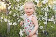 © vickyrandom - Cute baby girl on a background of white blossoms of an apple tree