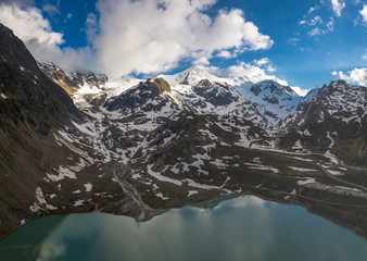 Wall Mural - glacier lake in the swiss alps during spring with clouds, blue sky and snow taken with a drone