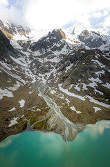 Wall Mural - glacier lake in the swiss alps during spring with clouds, blue sky and snow taken with a drone