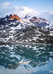 Wall Mural - glacier lake in switzerland in the alps during in the evening sky with clouds and warm lights and a lonely tree