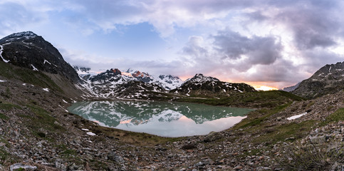 Wall Mural - glacier lake in switzerland in the alps during in the evening sky with clouds and warm lights and a lonely tree
