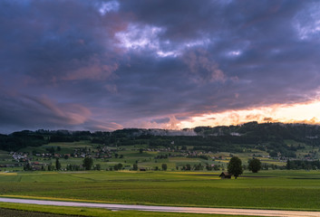 Wall Mural - valley and hills in switzerland during a sunny summer evening with warm light and colorful sky