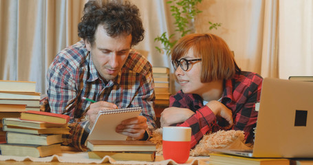 young couple study at home with many books and computer