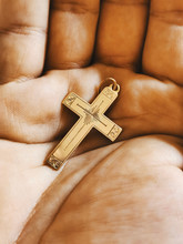 Close-up On A Golden Cross Pendant, In The Palm Of A Hand.