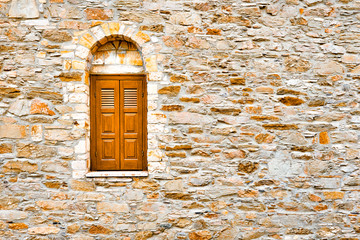 Arch window with stone wall. Wall with window background. Surface with asymmetrical stones. Old wall of ancient architecture. Fragment of historic building. Window with wooden shutters on stone wall