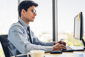 handsome confident businessman relaxing looking at technology of desktop computer monitor while sitt
