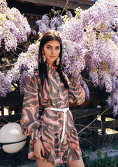 Wall Mural - sensual woman with dark hair in luxurious dress with accessories posing in summer garden with blooming trees