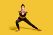 © khosrork - Athletic pretty girl with hair bun in tight sportswear doing sport, lower-body exercise, stretching hands out, warming up training muscles for flexibility. full length studio shot, isolated on yellow